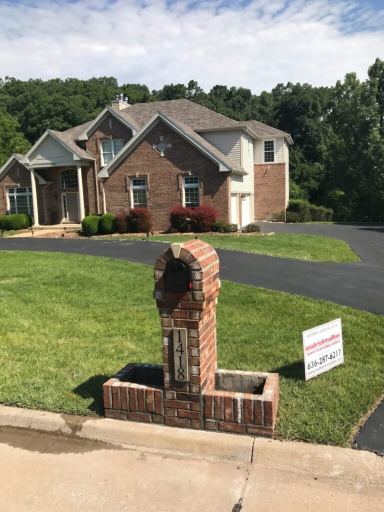 Arched brick mailbox flanked by two brick planter boxes, two-story brick house with gabled roof behind