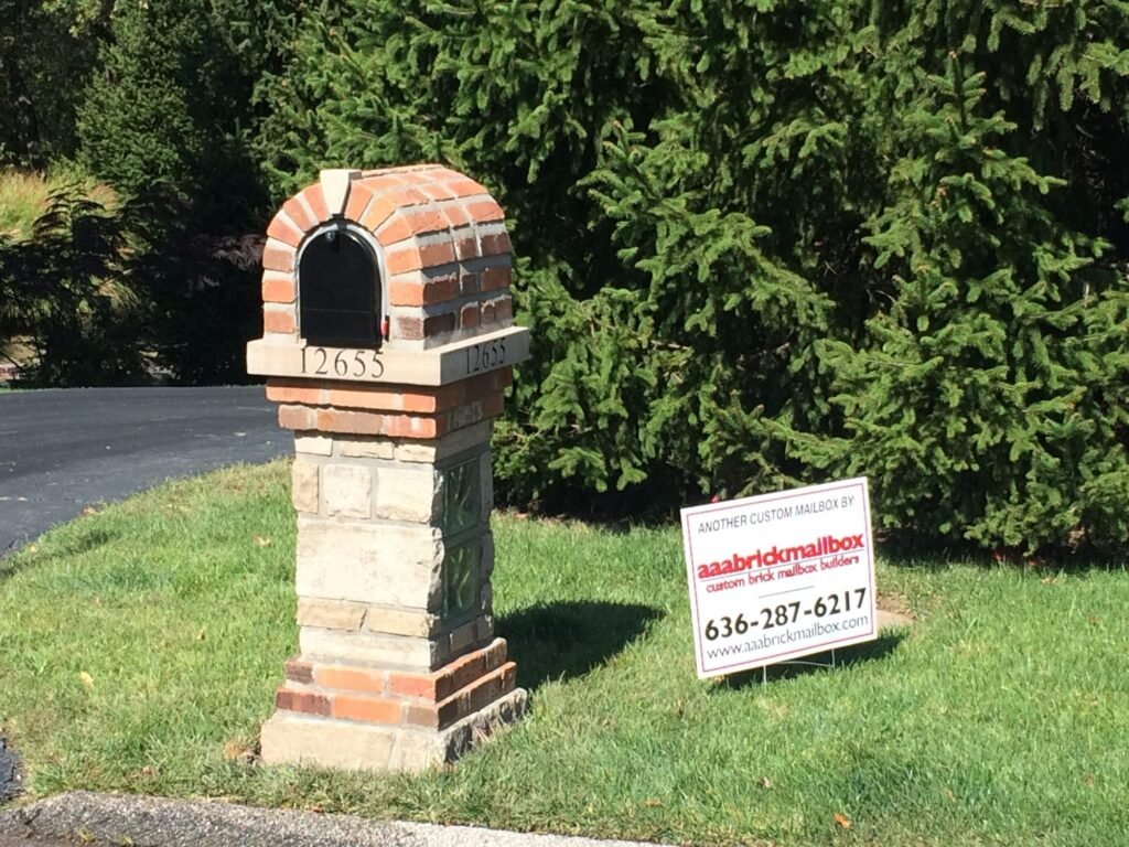 Orange-red brick arched dome top on a stacked stone pillar with dark glass block accent panels on two faces, number plaque mounted twice