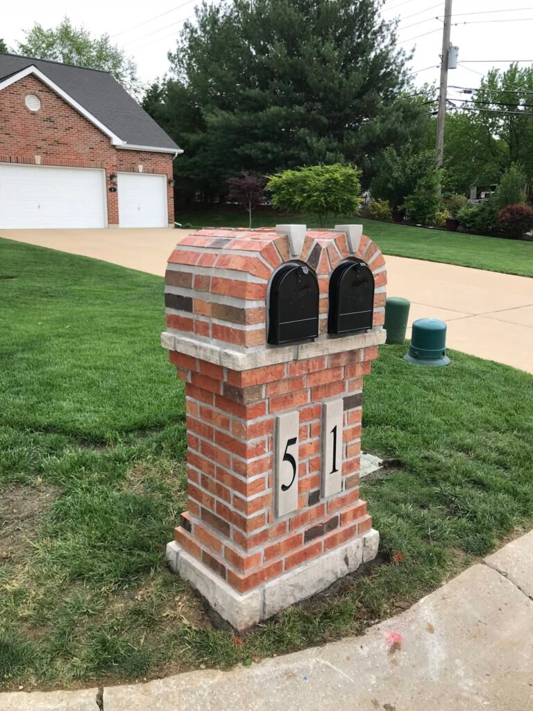 Double-door brick mailbox in red and brown brick with a stone cap and two stone address plaques